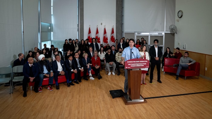 Justin Trudeau au lutrin lors d'une conférence de presse en compagnie notamment des ministres Chrystia Freeland et Harjit Sajjan à Vancouver le mercredi 27 mars 2024.