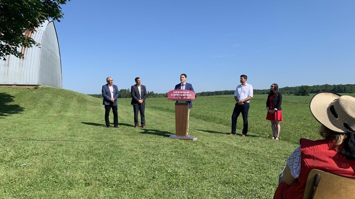 Le premier ministre et son équipe debout dans un champ à Enfield avec des éoliennes au loin.