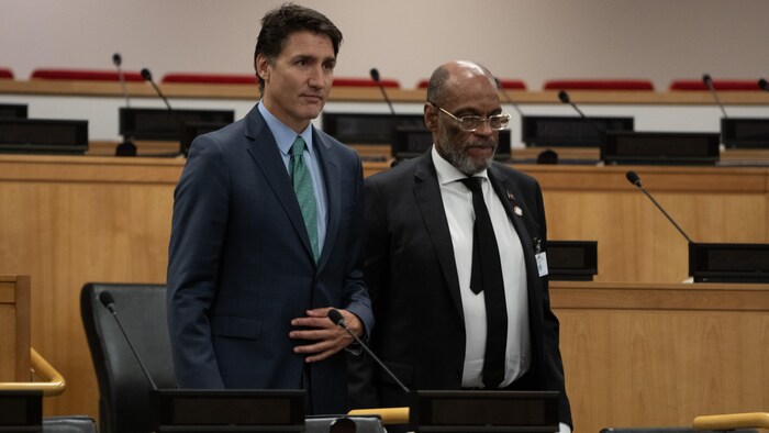 Justin Trudeau et Ariel Henry sont côte à côte debout, dans une salle de réunion. 