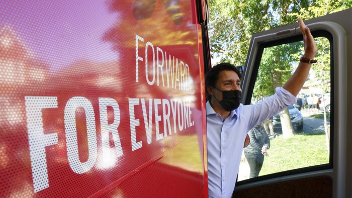 Justin Trudeau salue des partisans de la main à bord de son autobus de campagne.