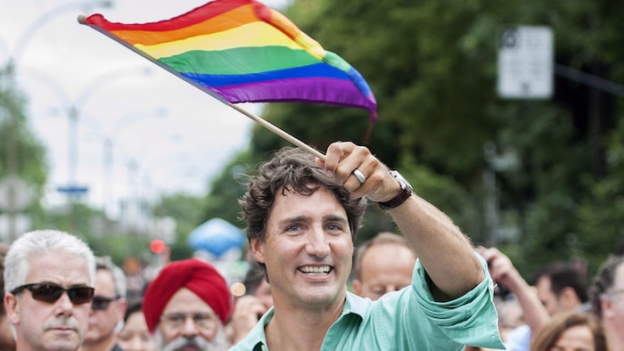 Justin Trudeau agite un drapeau arc-en-ciel lors d'un défilé.