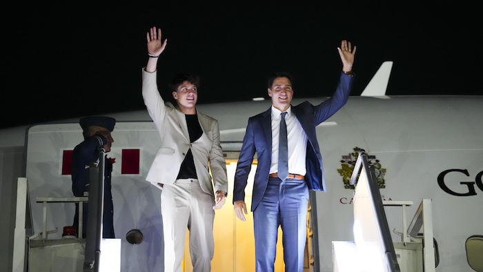 Justin et Xavier Trudeau font un salut de la main en descendant de leur avion. 