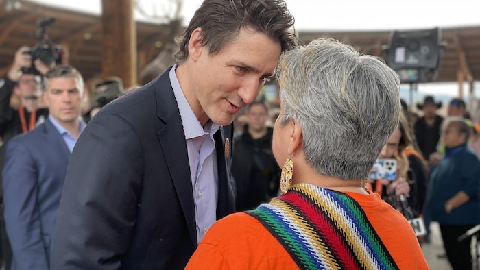 Le premier ministre Justin  Trudeau parle avec une femme en tenue orange.
