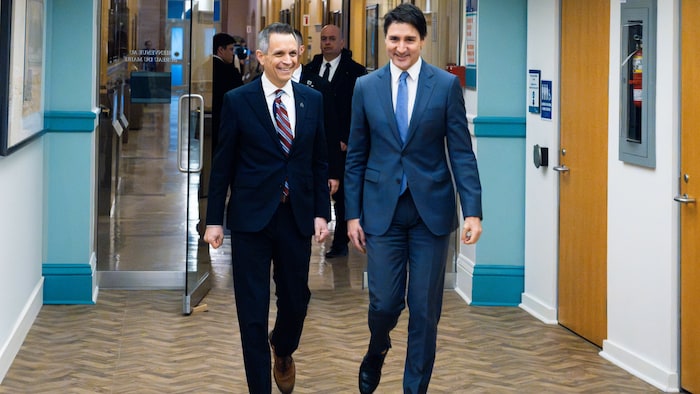 Le maire d'Ottawa Mark Sutcliffe et le premier ministre du Canada Justin Trudeau marchent ensemble dans les locaux de l'hôtel de ville.