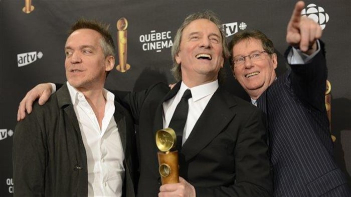 Los tres hombres sonríen en la alfombra roja.