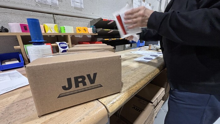 Un travailleur étiquette une boîte de livraison. 