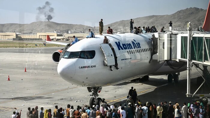 Personas encima de un avión mientras esperan en el aeropuerto de Kabul este lunes 16 de agosto.