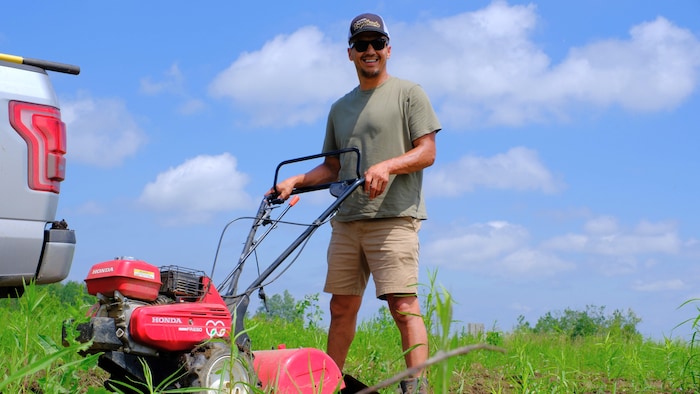 Jeremy Thompson étale du compost pour fertiliser la terre. 
