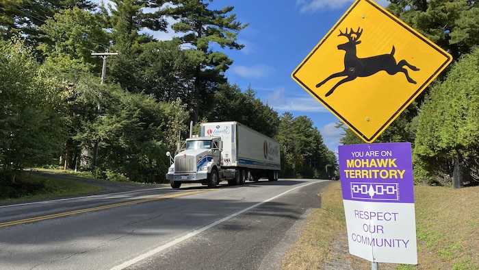 Un camion sur une route, à côté d'une pancarte indiquant une traverse de chevreuils.
