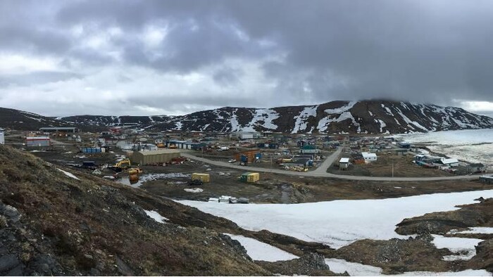 Des habitations en bas d'une montagne avec des traces de neige.