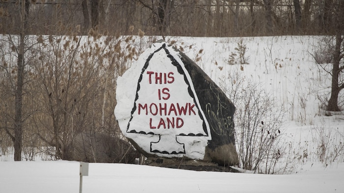 Un dessin sur une pierre, sur laquelle est peint « This is mohawk land ».