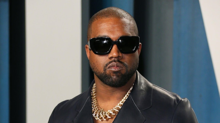 Kanye West porte une veste de cuir et des lunettes fumées.