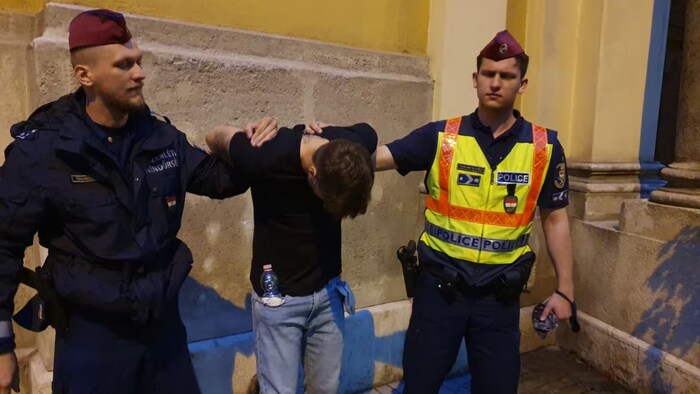 Deux policiers hongrois tiennent par le bras Oliver Karafa lors de son arrestation.