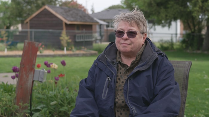 Karen Miller est assise dans son jardin.