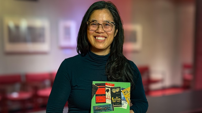 Karen Tam tenant un exemplaire de son livre « Whose Chinatown? »