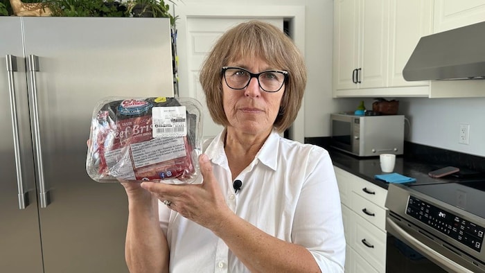 La femme tient dans ses mains la barquette de viande.