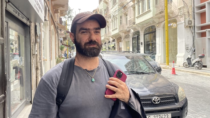 Un homme portant une casquette est debout dans une rue.