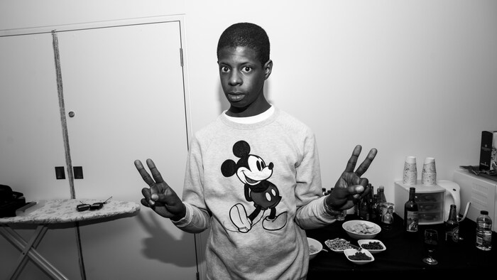 Karim Ouellet en noir et blanc qui fait des signes de paix avec ses deux mains.