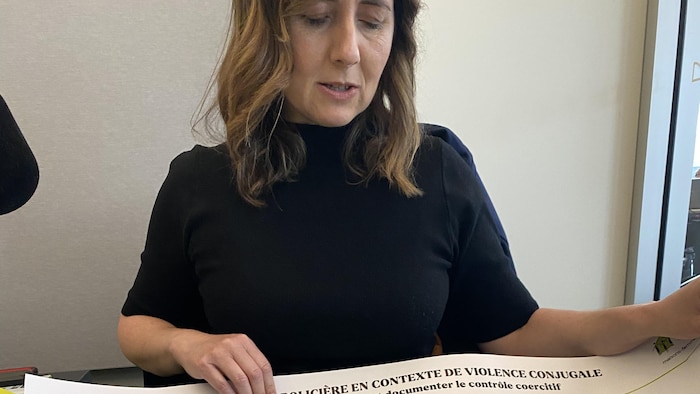 L’avocate et chargée de projet au Regroupement des maisons pour femmes victimes de violence conjugale, Karine Barrette, montre une affiche préparée par l'organisme pour les corps policiers.