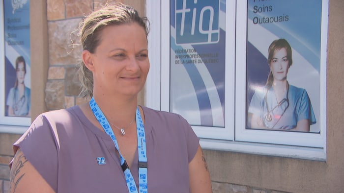 Une dame pose devant une affiche d'infirmière