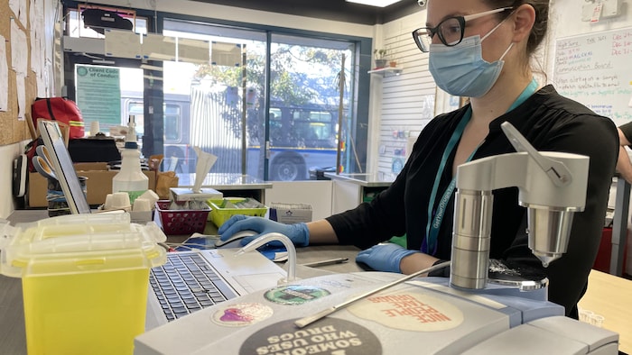Une femme avec un masque est assise dans un laboratoire.