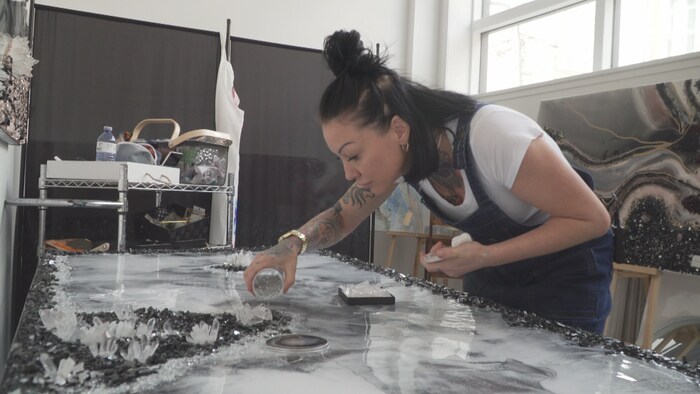 L'artiste verse du verre concassé sur sa toile.