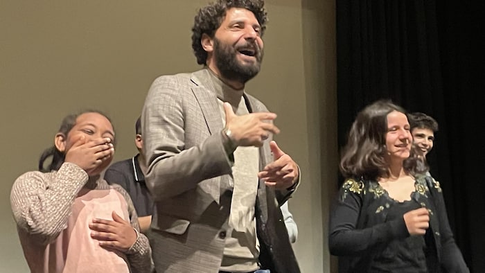 Un homme entouré de jeunes en train de rire.