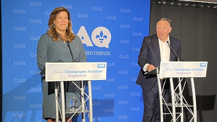 Kateri Champagne Jourdain et le premier ministre, François Legault, devant la bannière de la CAQ et derrière des lutrins.