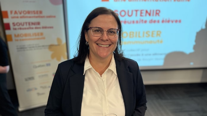 Kathleen Baldwin pose devant un écran lors d'une conférence. Elle sourit pour la photo.
