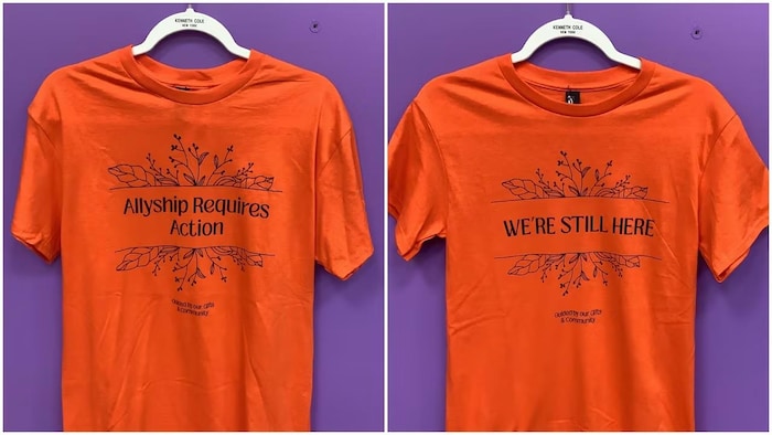 Deux chandails orange vendus à Guided by Our Gifts portant les messages « Allyship Requires Action » et « We’re Still Here » sont suspendus côte à côte.