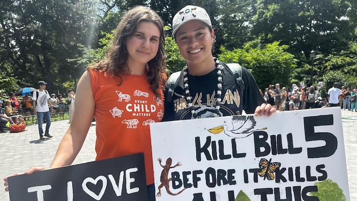 Kayah Adamuszewski et Tausani Levale tiennent des pancartes lors d'une manifestation contre la Loi de 2025 pour protéger l’Ontario en libérant son économie.