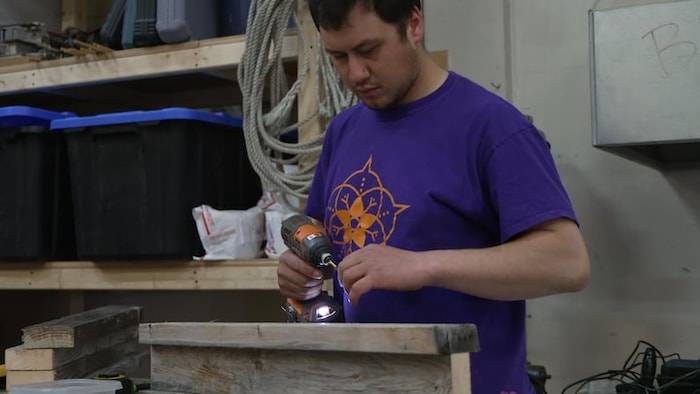 Un homme tient un outil dans un atelier de construction.