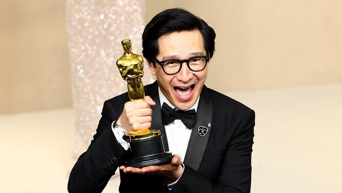 On voit l'acteur souriant avec le trophée dans les mains.