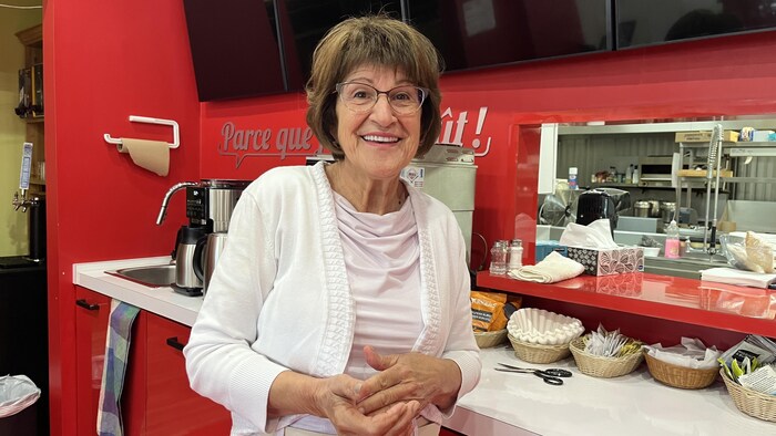Un femme sourit pour une photo dans un restaurant.