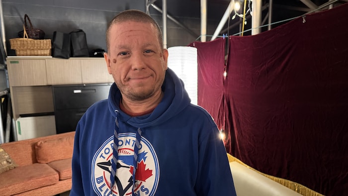 Un homme qui porte un chandail des Blue Jays de Toronto, souriant.