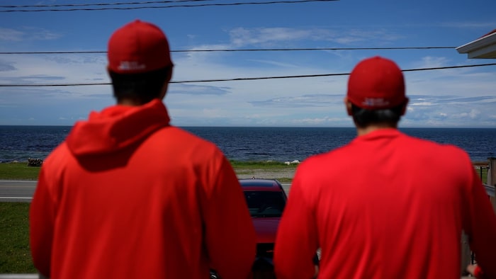 Deux hommes en tenue de baseball sont face à la mer.