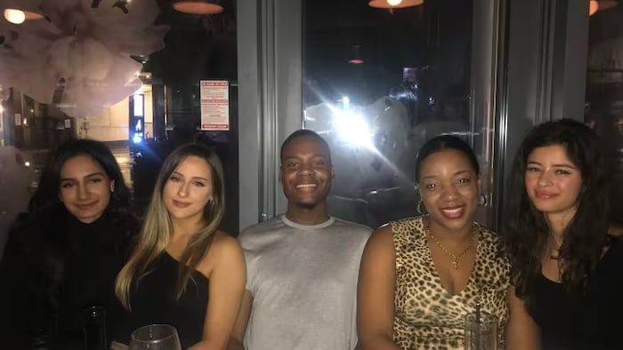 Kemo Montique, centre, is pictured with friends at a restaurant. The 27-year-old is facing deportation despite living in Canada since 2007. (Submitted by Kemo Montique)
