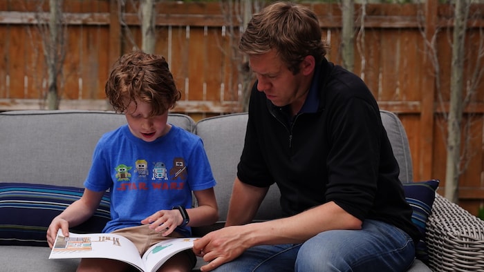 Liam lit un livre et Ken regarde, à l'extérieur.
