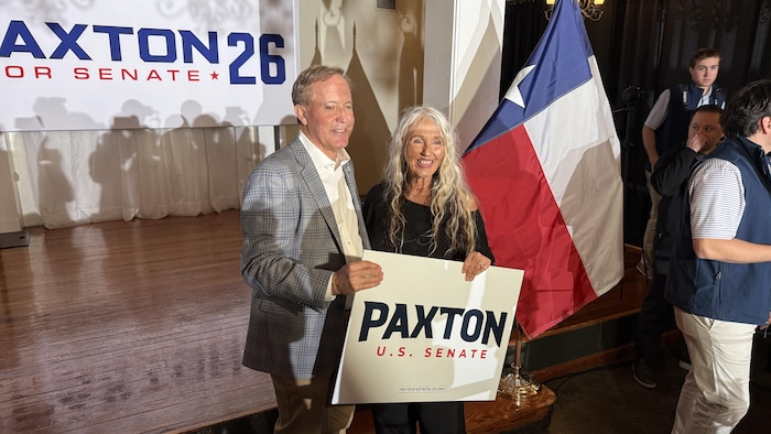 Ken Paxton en compagnie d'une électrice, tenant une pancarte au nom du candidat.
