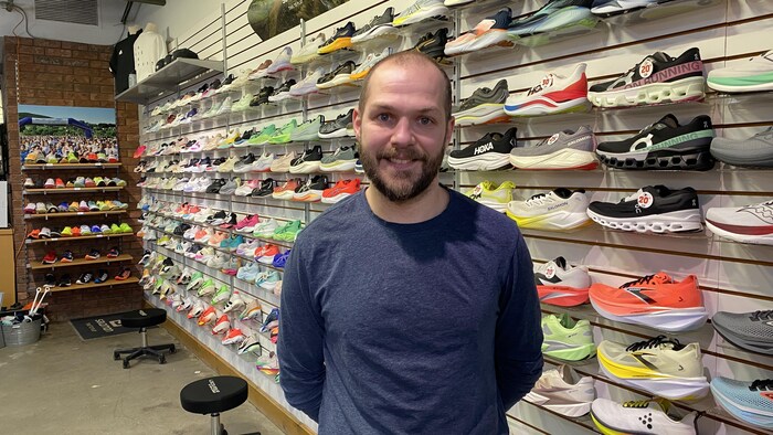 Kenny Beaudette pose devant un mur de souliers.