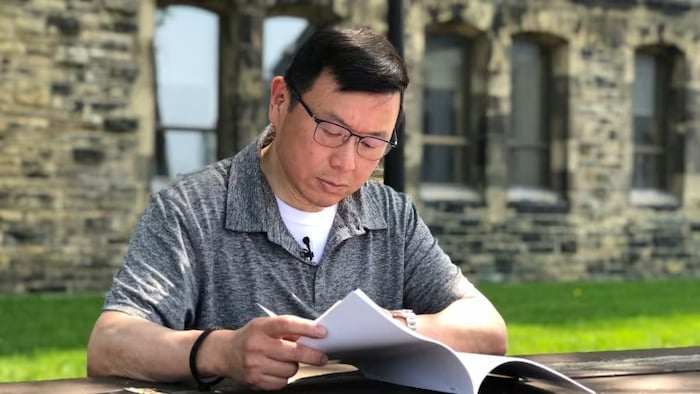 Former Conservative MP Kenny Chiu reads through former governor general David Johnston's first report on election interference. Chiu said he is "disappointed" Johnston didn't recommend a public inquiry. (Ashley Burke/CBC)