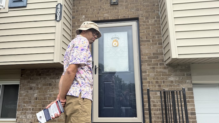 Derek Pardue attend devant une porte dans un quartier résidentiel du Kentucky.