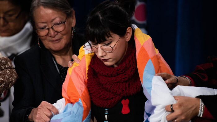 Une jeune femme se fait offrir une couverture.