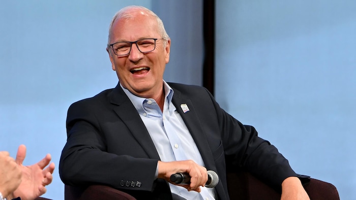 Un homme sourit alors qu'il participe à un panel.