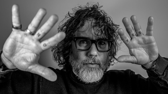 Photo en noir et blanc d'un homme portant des lunettes. 