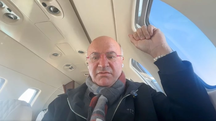 Kevin O'Leary est assis dans un avion privé à côté d'un hublot.