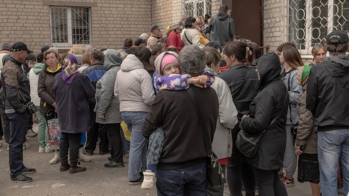 Des personnes font la queue devant un immeuble.