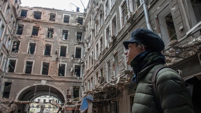 Un jeune homme porte son regard vers un édifice en ruine.