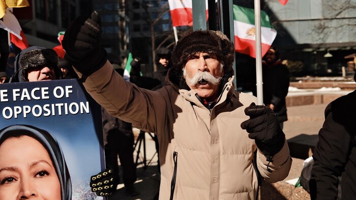 Khosrow Ziaei manifeste et brandit un drapeau.