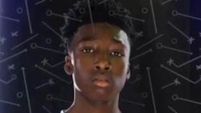 Le jeune pose en uniforme de basketball.